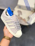 Adidas Superstar sneakers, featuring a light grey suede upper