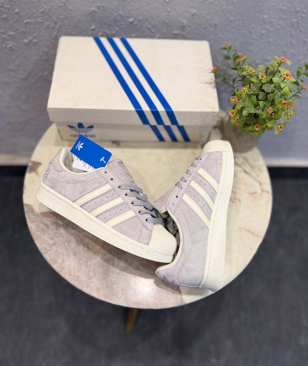 Adidas Superstar sneakers, featuring a light grey suede upper