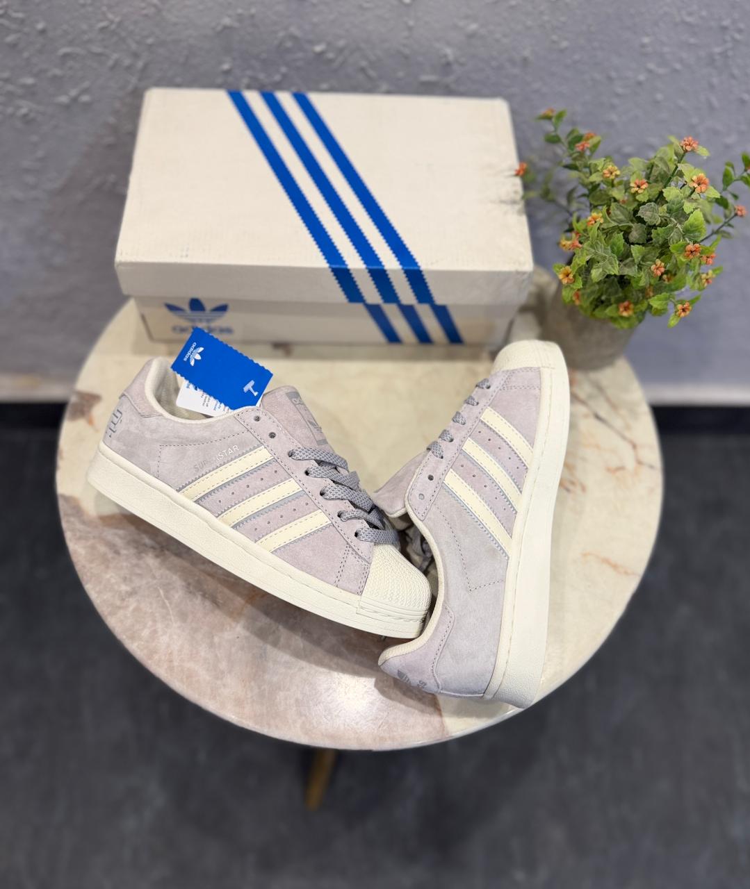 Adidas Superstar sneakers, featuring a light grey suede upper